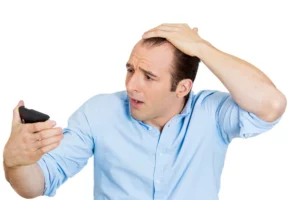 Closeup portrait of shocked man feeling head, surprised he is losing hair, receding hairline or seeing bad news on cellphone, isolated on white background.